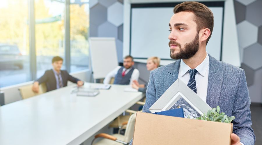 man walking out of conference room holding a box