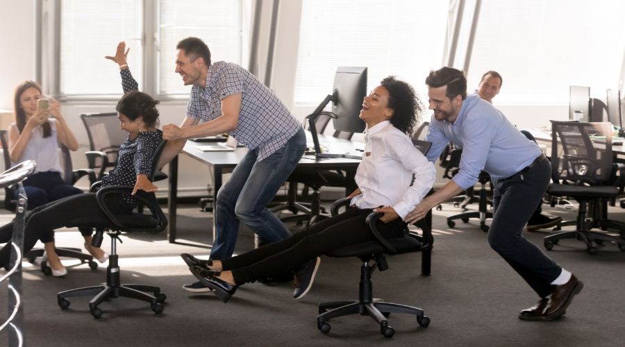 employees laughing and holding a chair race