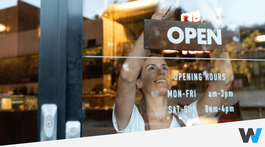 Happy small business owner hanging an "Open" sign