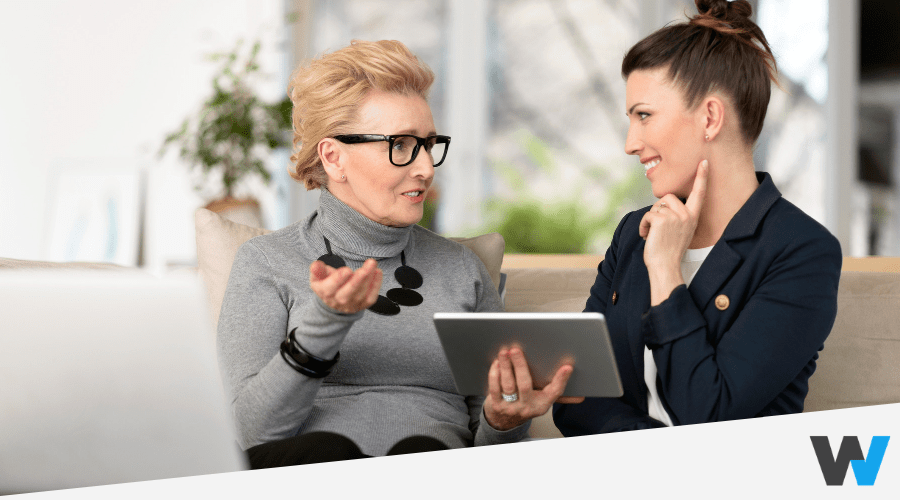 smiling young and old businesswomen talking and using a tablet