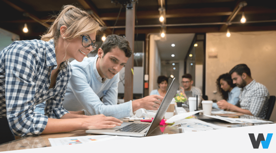 young woman and man in casual clothes looking at a laptop over people background