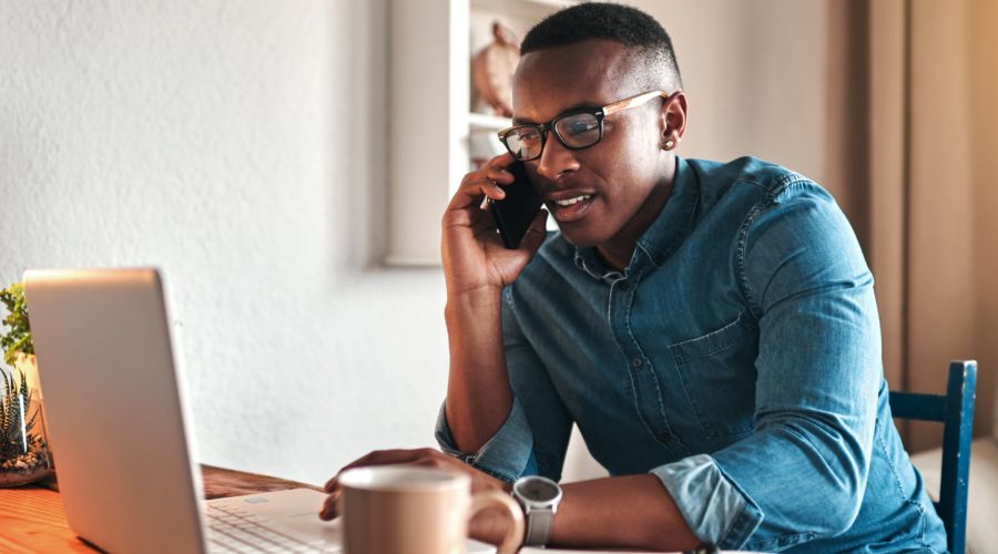 business man working on laptop and talking on cellphone as he works from home