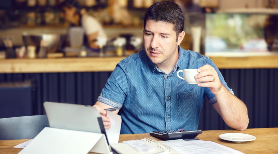 small business owner drinking coffee and calculating how much to pay himself