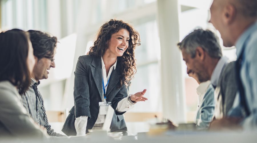 Happy small business owner talking with her staff during a meeting