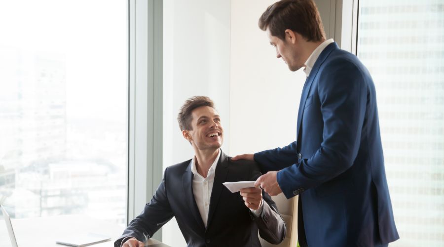 business owner handing employee a year-end bonus check