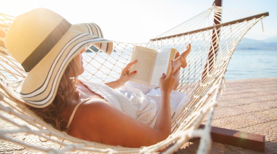 woman reading a book in a hammock on the beach