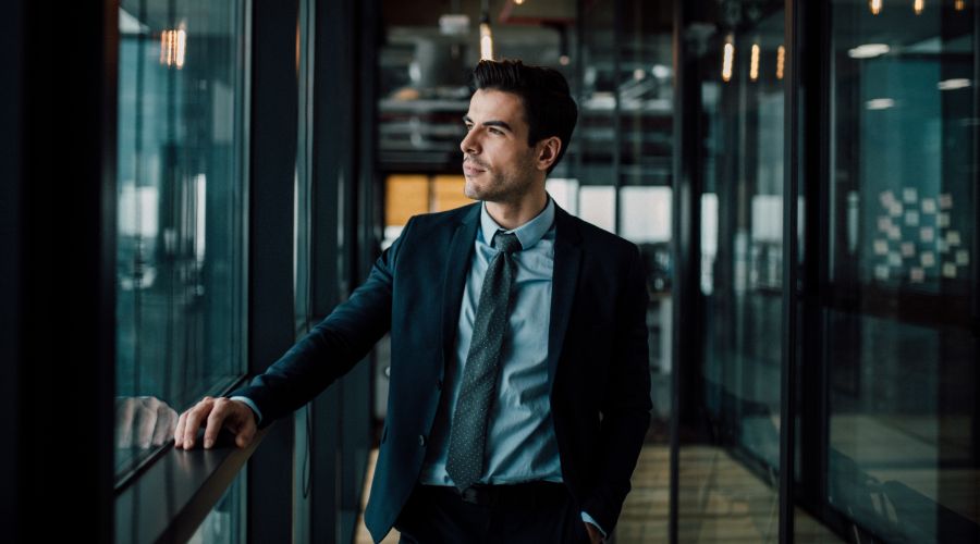 businessman looking out a window while trying to make a decision