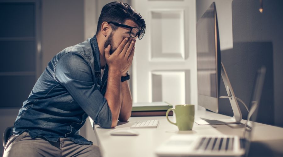 Professional man rubbing his eyes in front of his computer