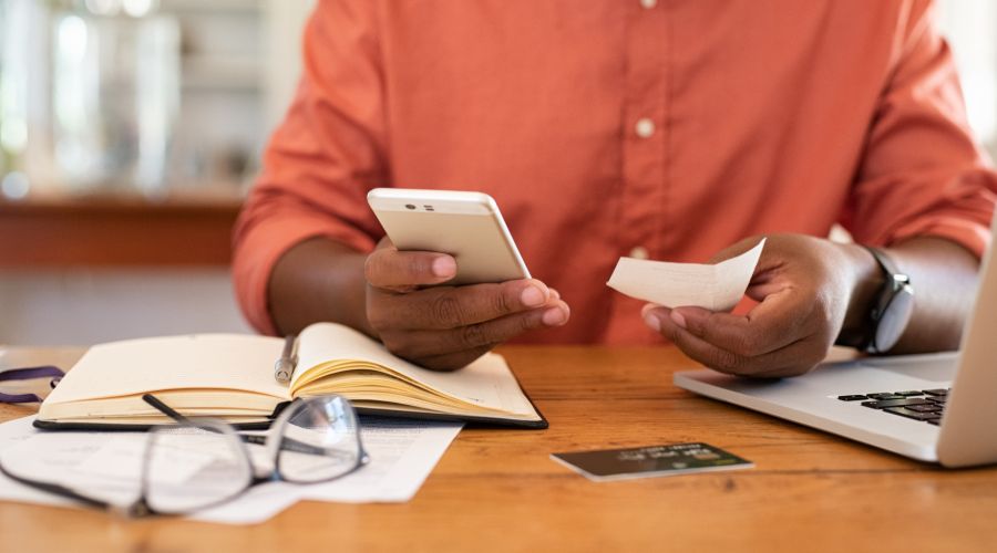 man holding a receipt and entering reimbursement request into his phone using mobile expense management program