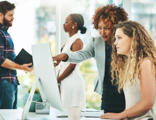 Two businesswomen looking at digital documents on a computer